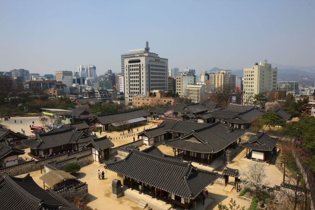 Aerial view of Namsangol Hanok Village rooftops against the Seoul skyline