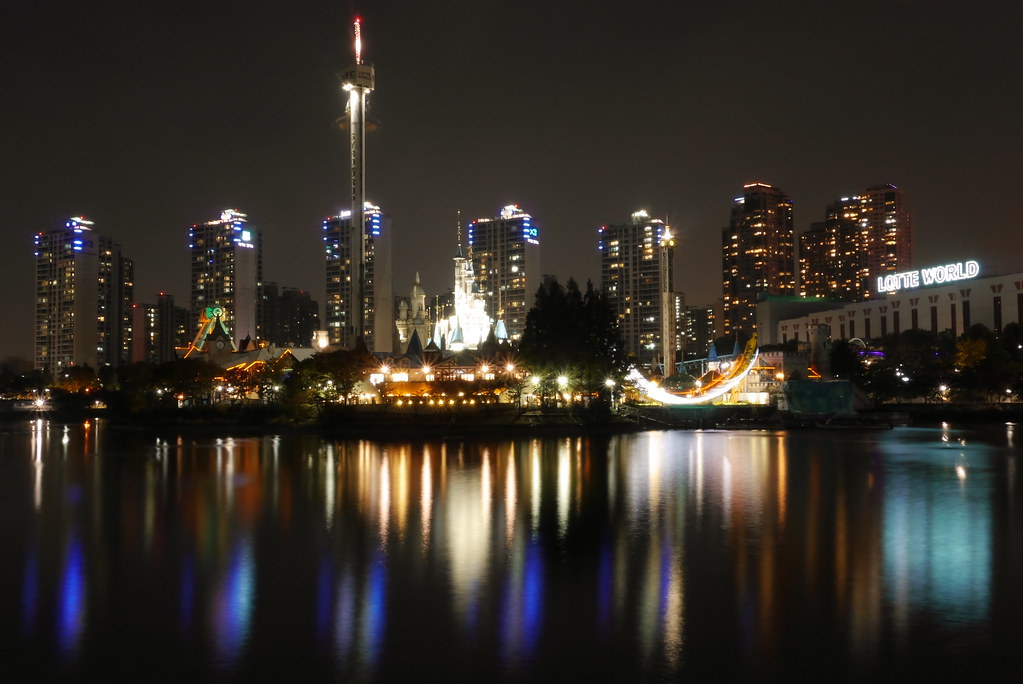Lotte World Magic Island castle lit at night reflected on Seokchon Lake