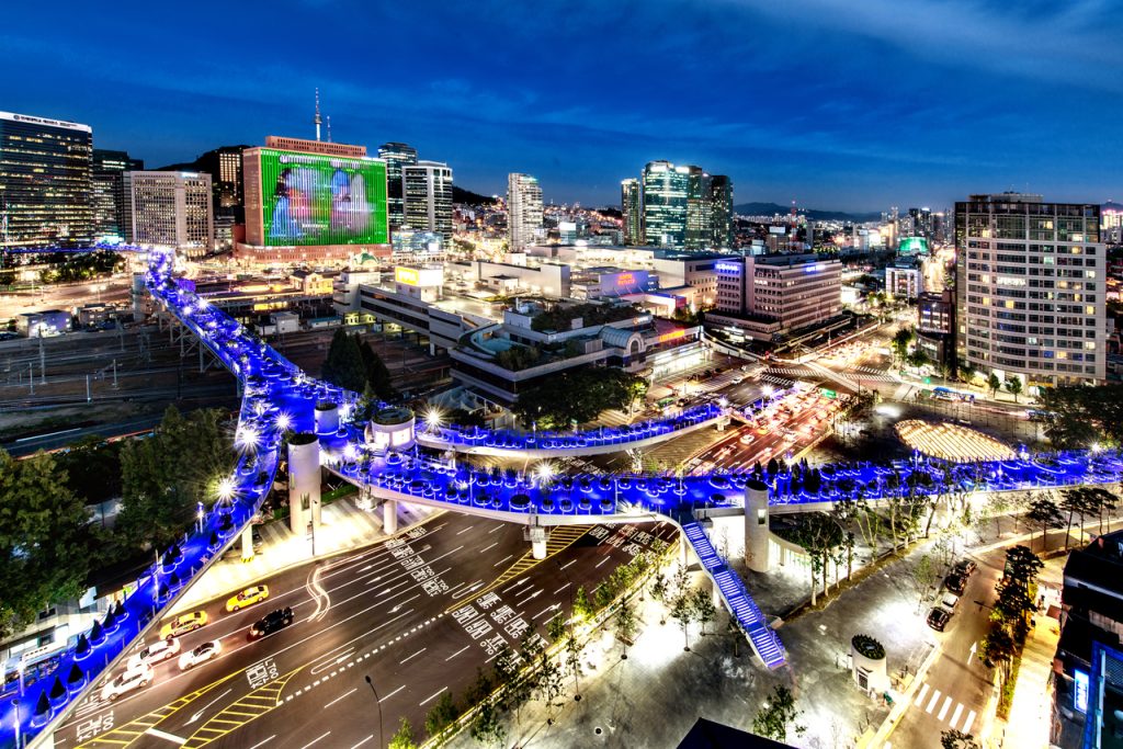 Seoullo 7017 elevated walkway lit by blue LED lamps at night above central Seoul