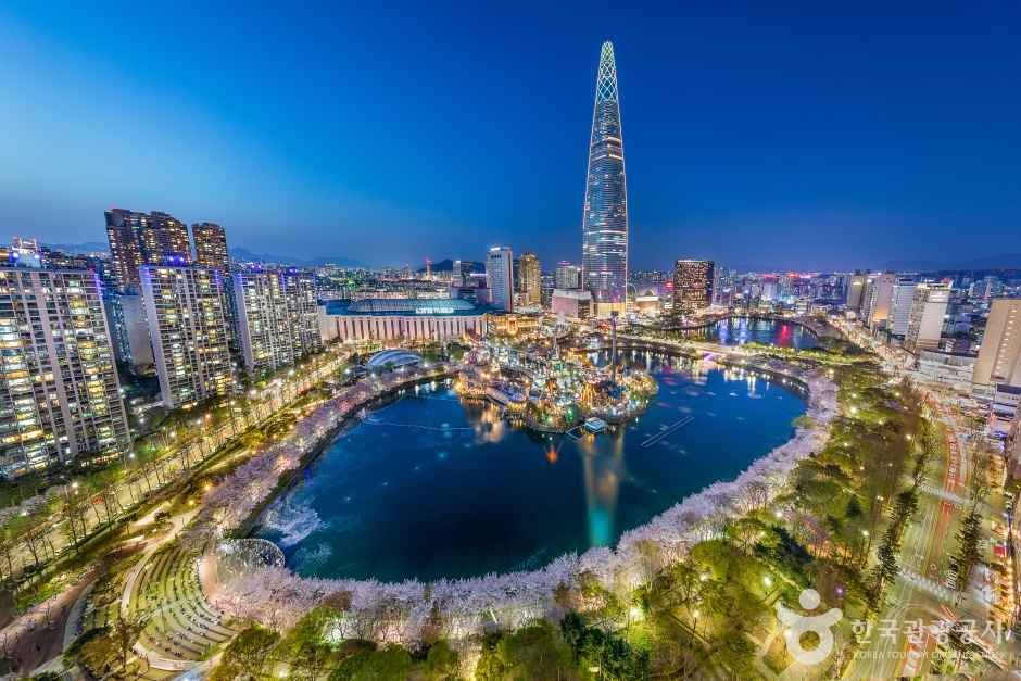 Seokchon Lake cherry blossoms beneath Lotte World Tower at dusk