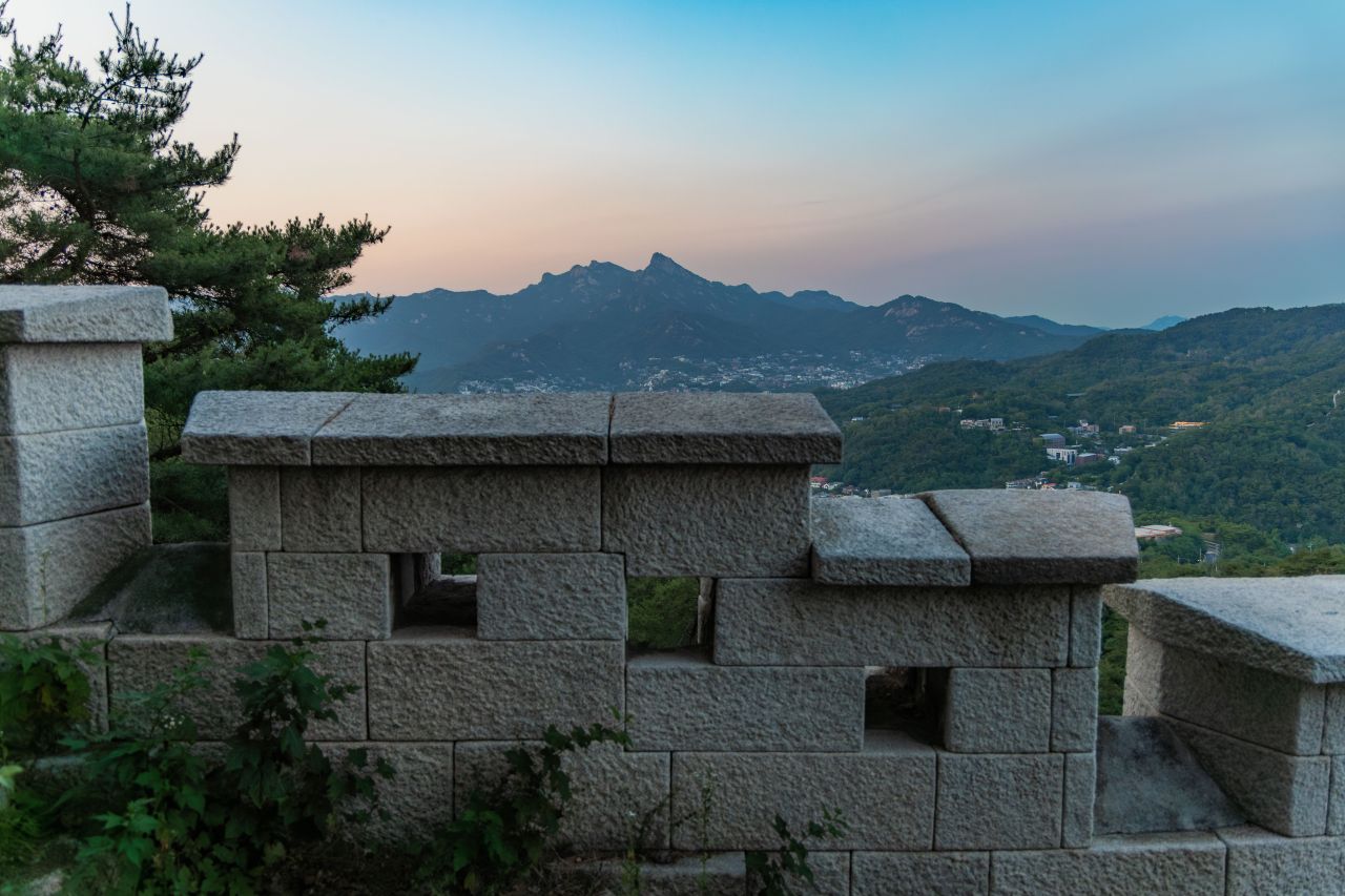 Seoul City Wall on Inwangsan at sunset with mountain peaks beyond