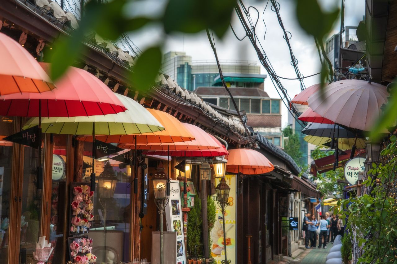 Colorful umbrellas and lanterns over shops in an Ikseon-dong Hanok Village alley