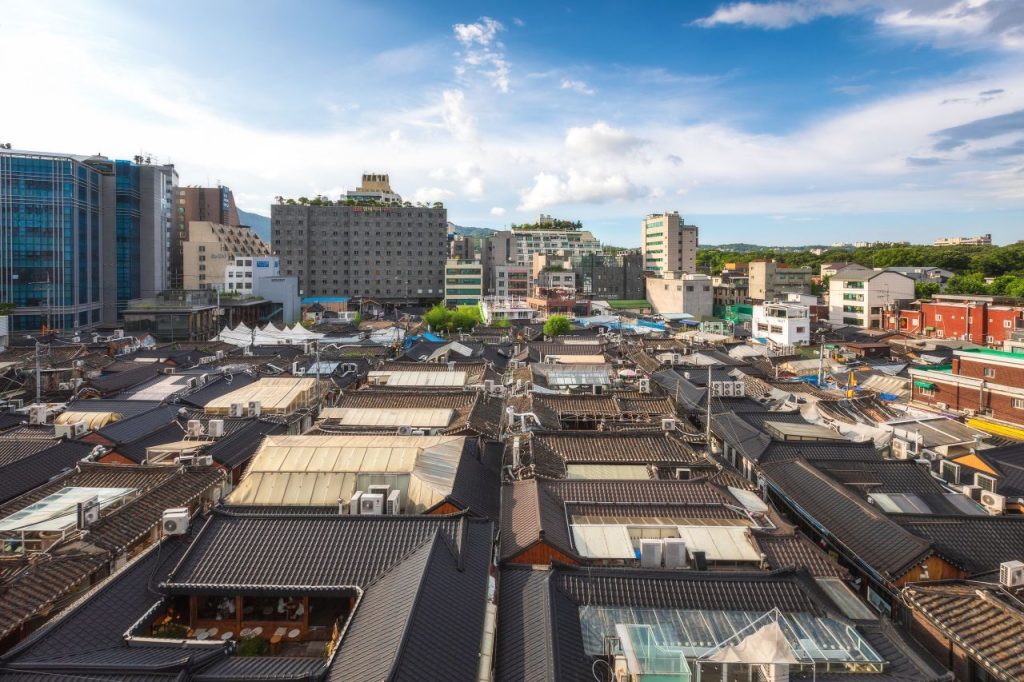 Aerial view of Ikseon-dong Hanok Village tiled rooftops against the Seoul skyline