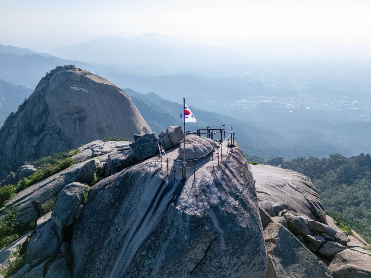 Baegundae summit of Bukhansan National Park with Korean flag and Seoul view