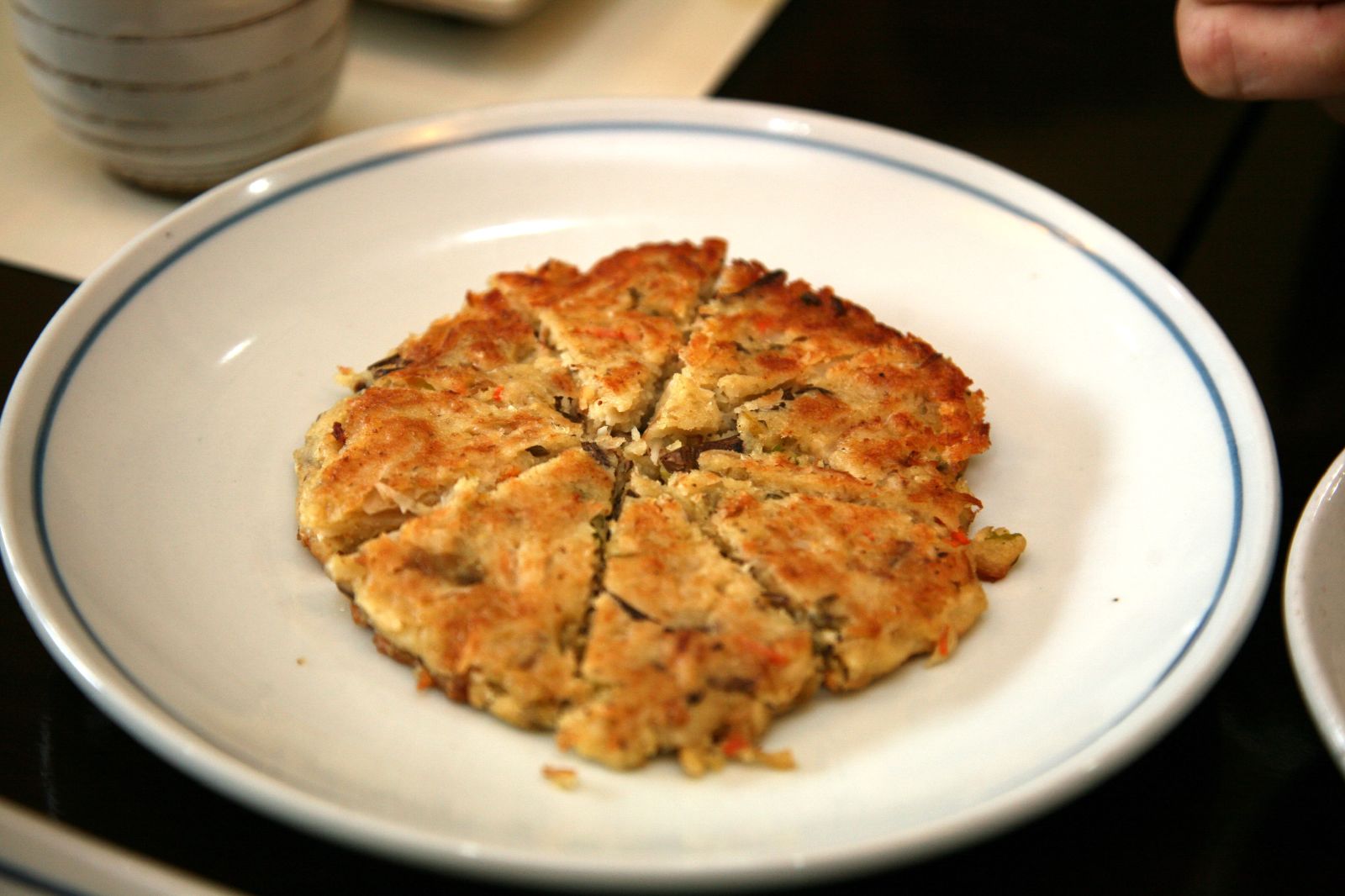 Bindaetteok mung-bean pancake cut into wedges on a plate, Korean street food