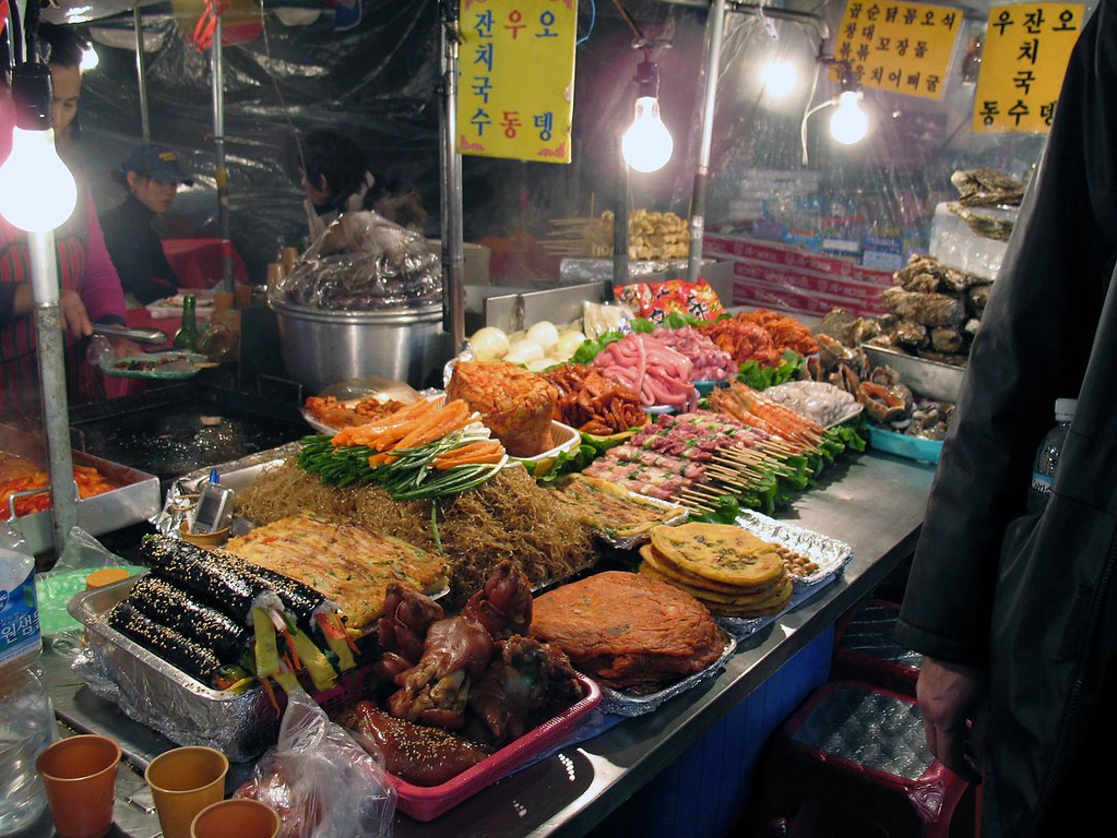 Korean street-food stall with Hangul signage and rows of food at a Seoul market