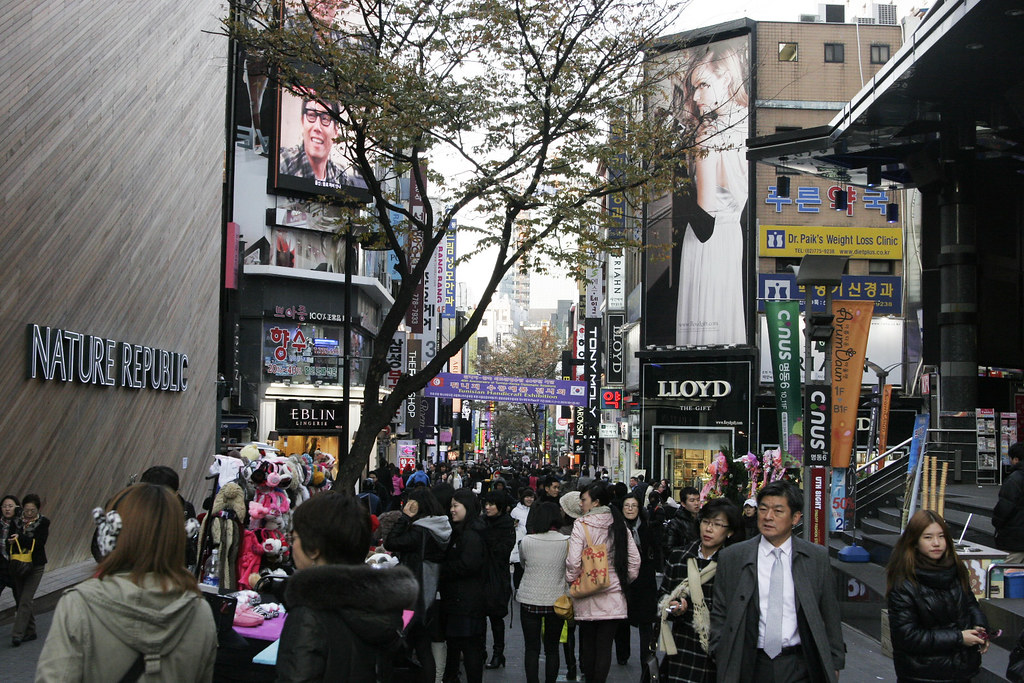 Crowded Myeongdong shopping street with K-beauty stores and Korean signage, Seoul