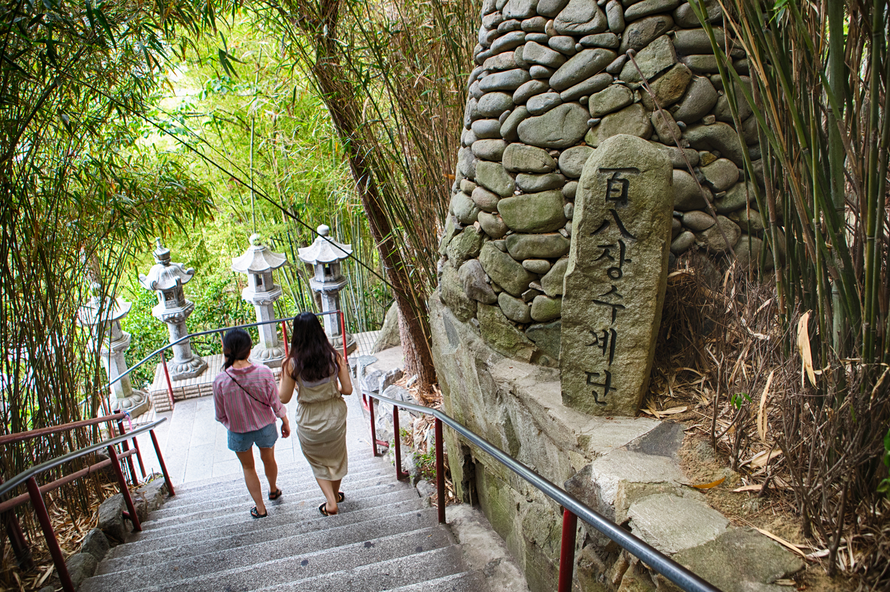 The 108-step long-life staircase and its stone marker descending through bamboo at Haedong Yonggungsa