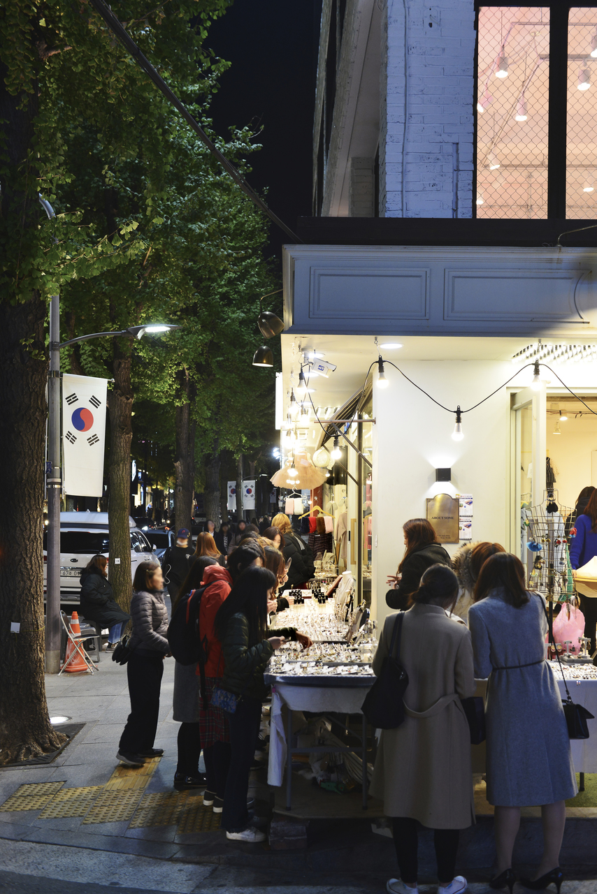 Shoppers at a sidewalk stall on Garosu-gil under ginkgo trees, Seoul