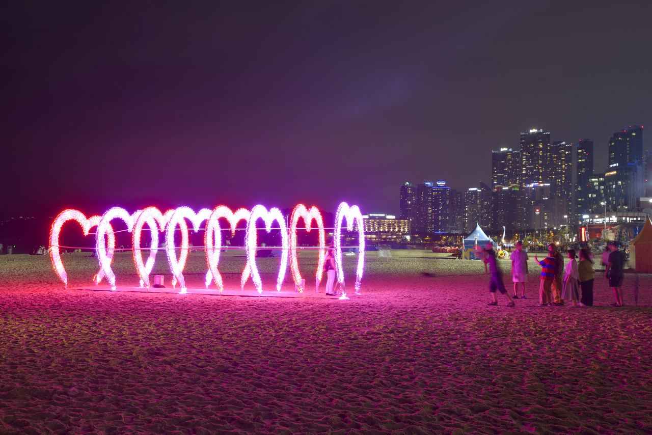Haeundae Beach at night with the lit Busan skyline behind the sand