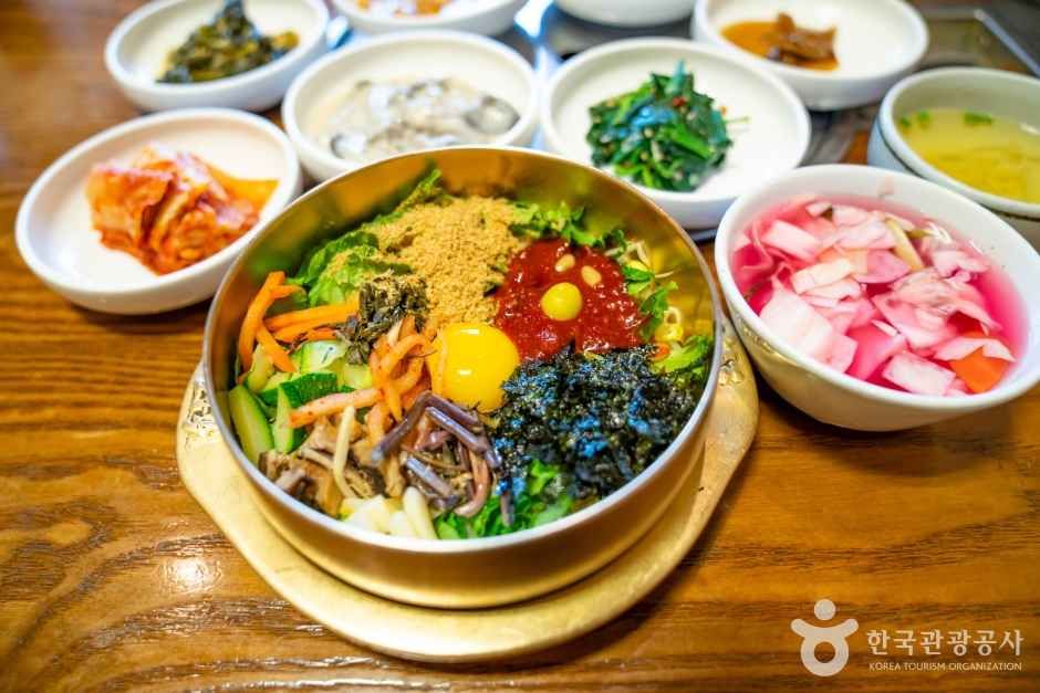 Jeonju bibimbap in a brass bowl with banchan side dishes