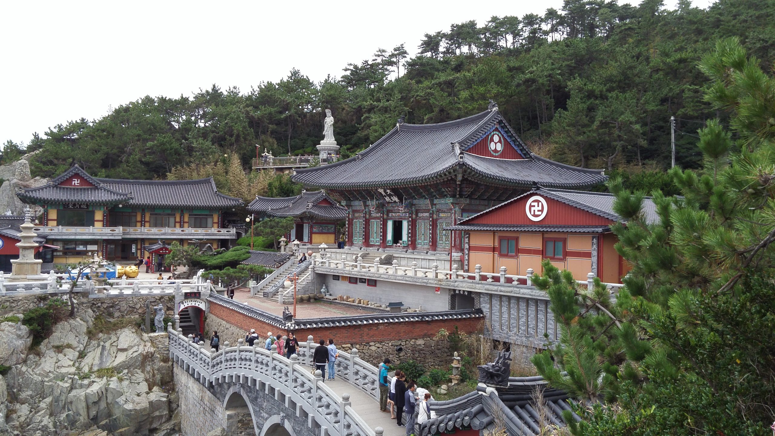 Visitors crossing the Yongmun stone bridge below the main hall at Haedong Yonggungsa