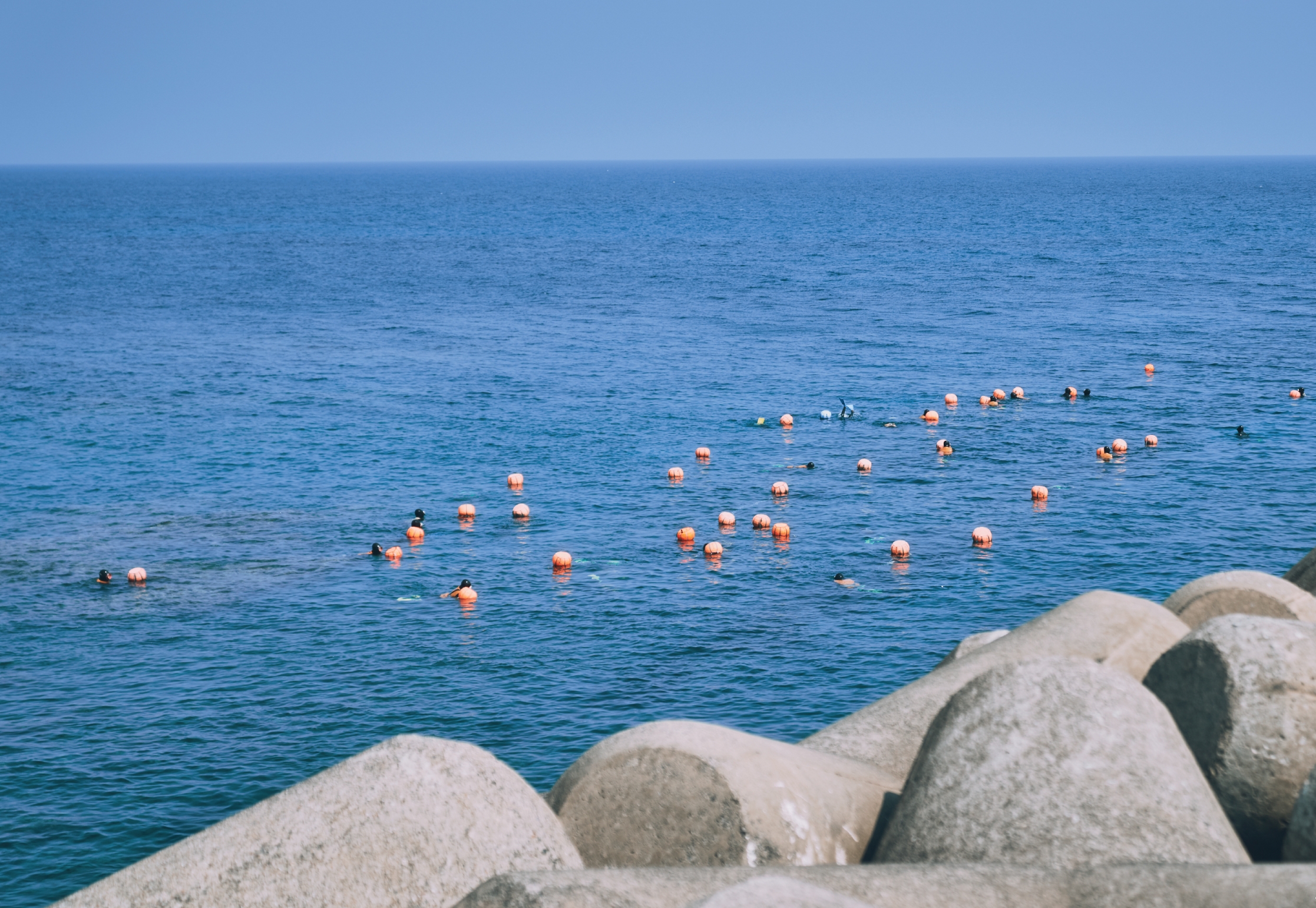 Jeju haenyeo divers with orange floats in the sea near Seongsan
