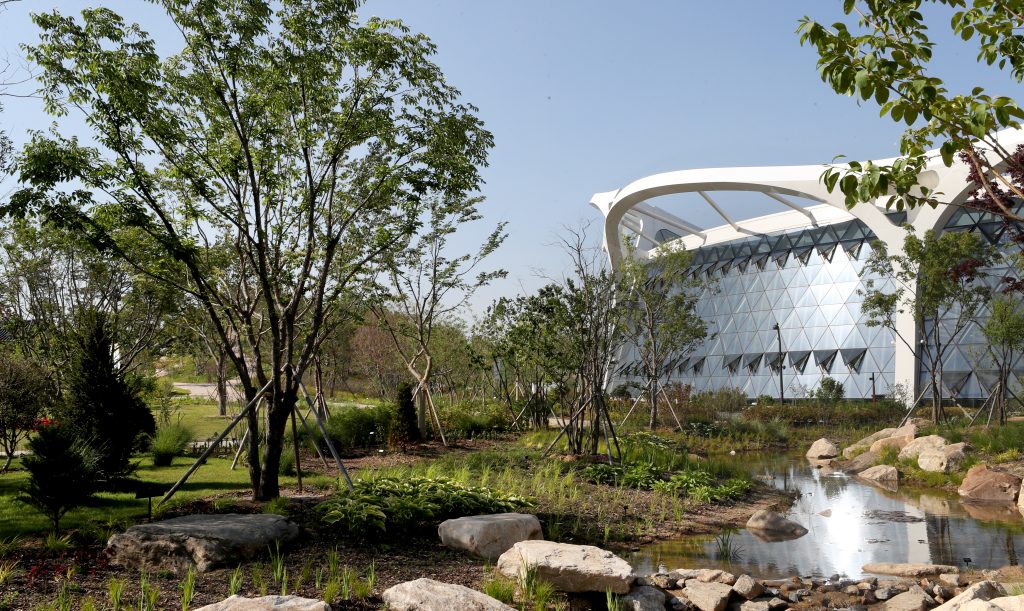Seoul Botanic Park's dish-shaped glass greenhouse seen across the garden in Magok