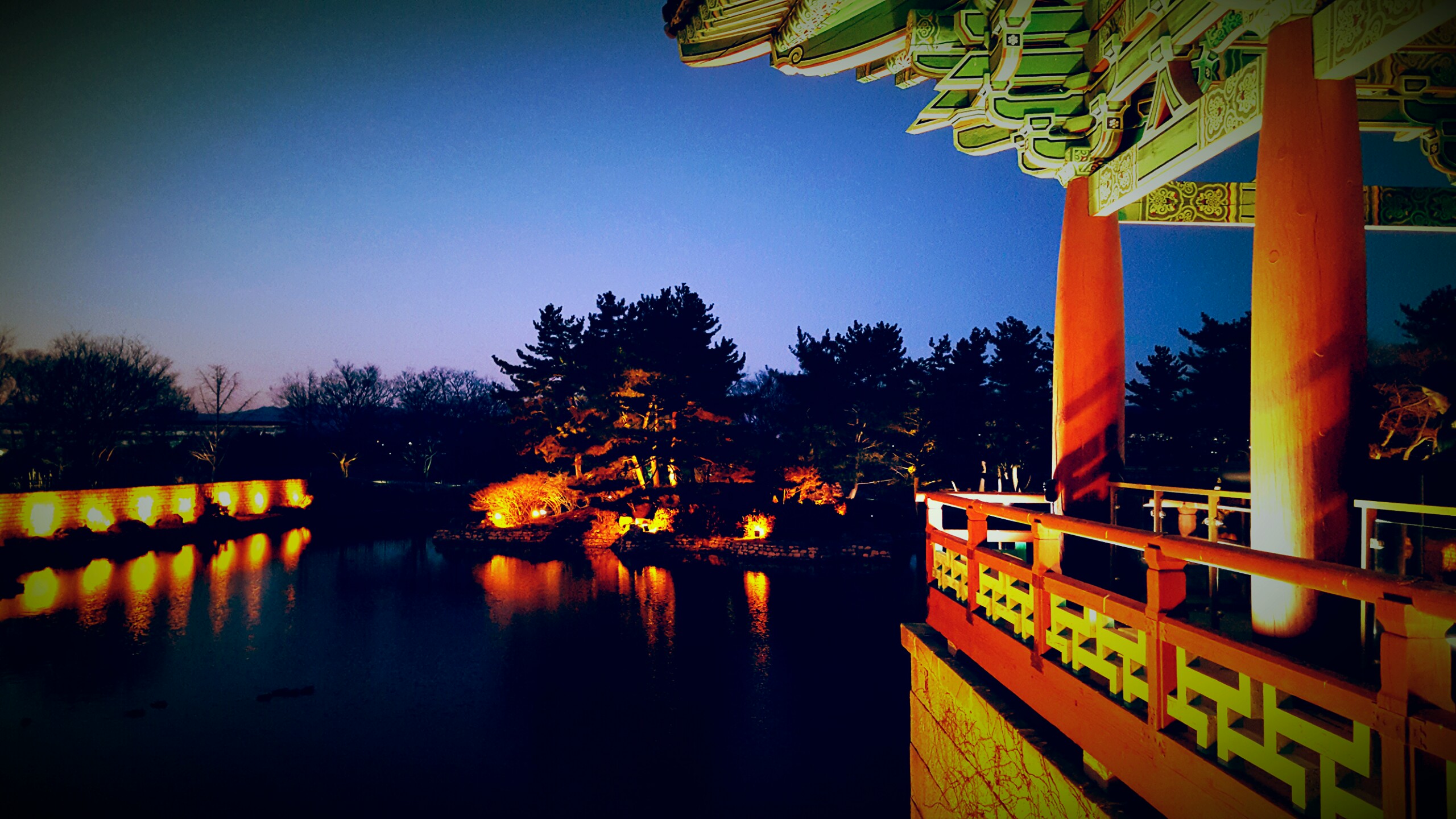 Blue hour view across Wolji Pond from inside a lit pavilion