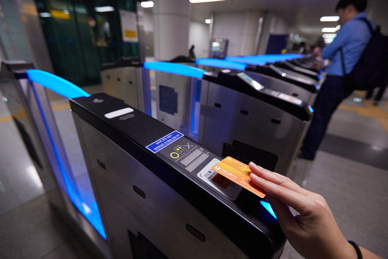 Row of Seoul subway fare gates with a passenger tapping a transit card