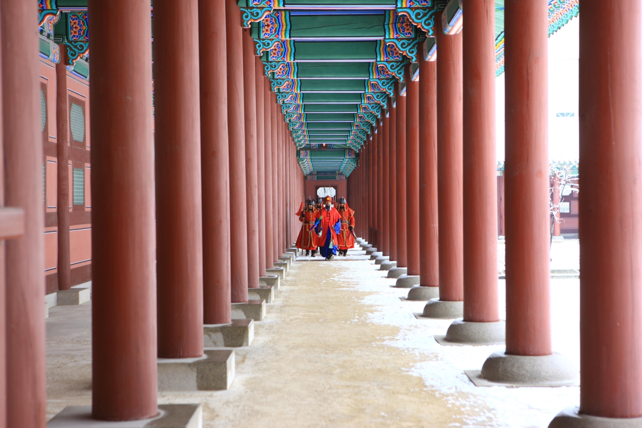 Royal guards in ceremonial dress walking a colonnade at Gyeongbokgung Palace