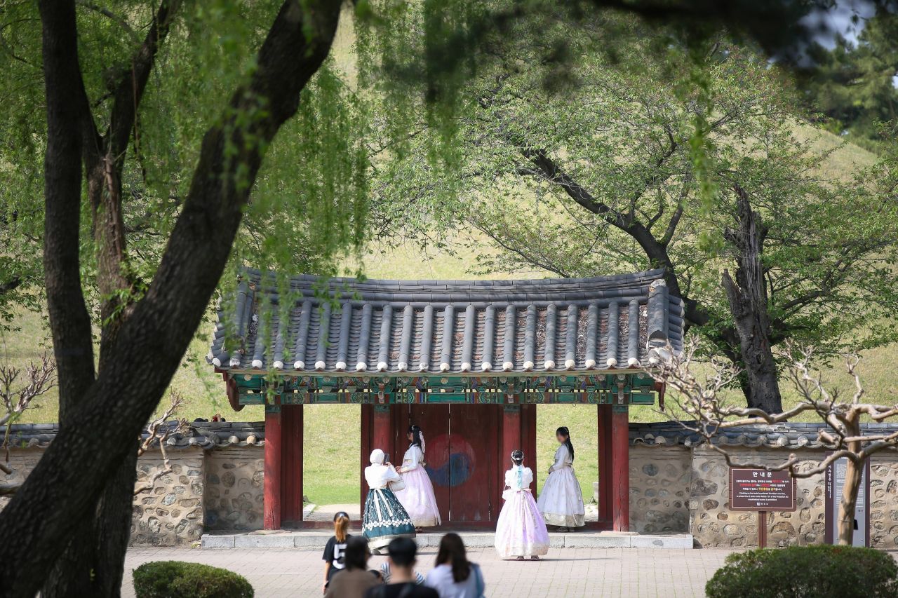 Visitors in hanbok at a traditional gate of Daereungwon