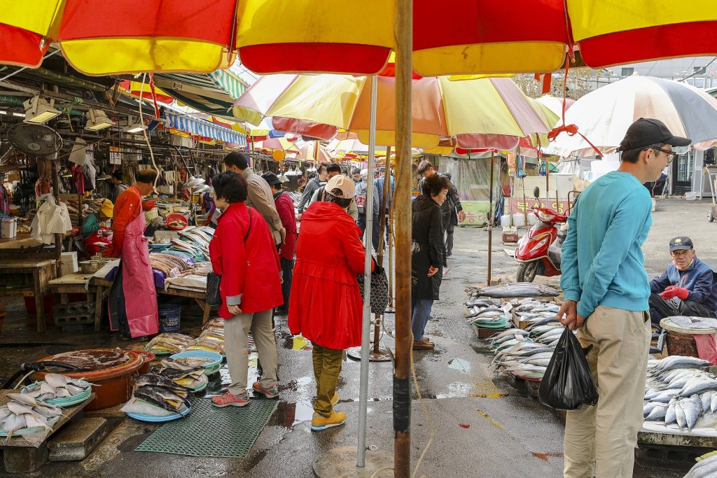 Shoppers under umbrellas at the outdoor fish stalls of Jagalchi Market in Busan
